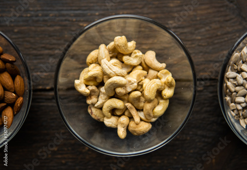 Almond, cashew and sunflower seeds in a small plates which standing on a vintage wooden table. Nuts is a healthy vegetarian protein and nutritious food.