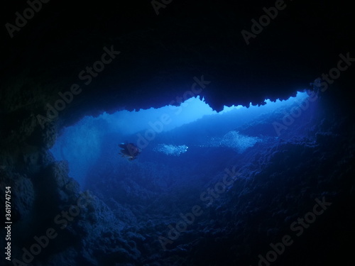 cave diving underwater scuba divers exploring caves ocean scenery sun beams and rays background © underocean