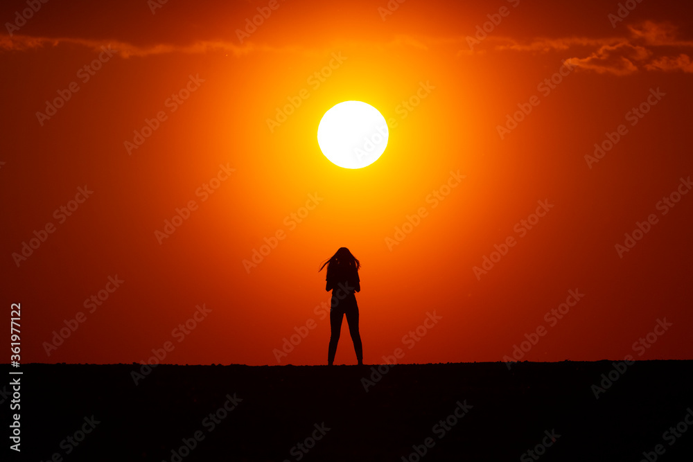 Young woman silhouette at sunset on a farm.