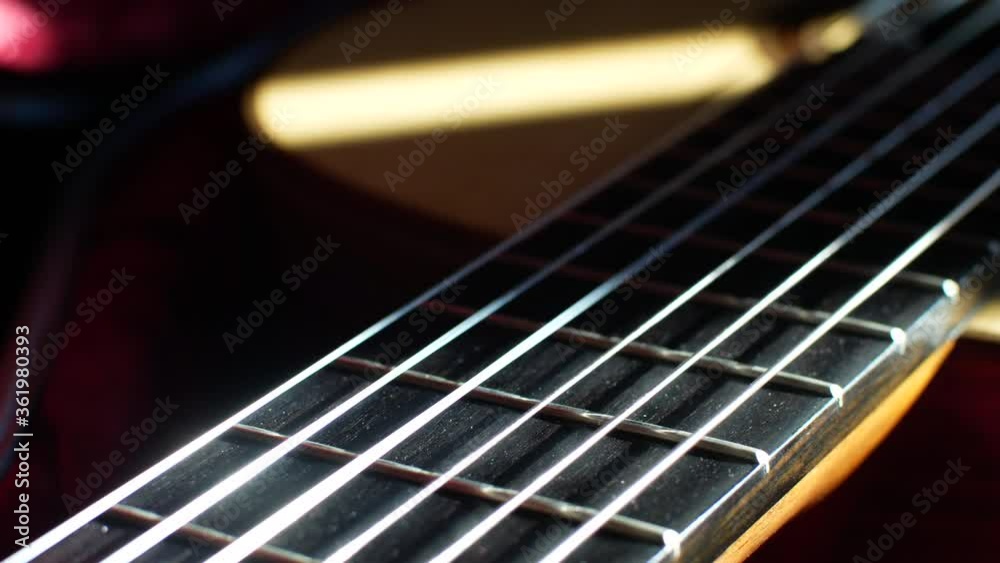 Guitar fretboard with frets and strings close up sliding shot with sunlight shining on the sound board Guitar fretboard with frets and strings close up sliding shot with sunlight shining on the sound board