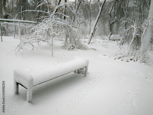 Tall white snow lies on a bench and tree branches. Kishinev. Moldova.
