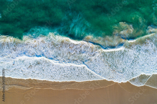 Aerial view beach waves, blue/green ocean, golden sandy beach
