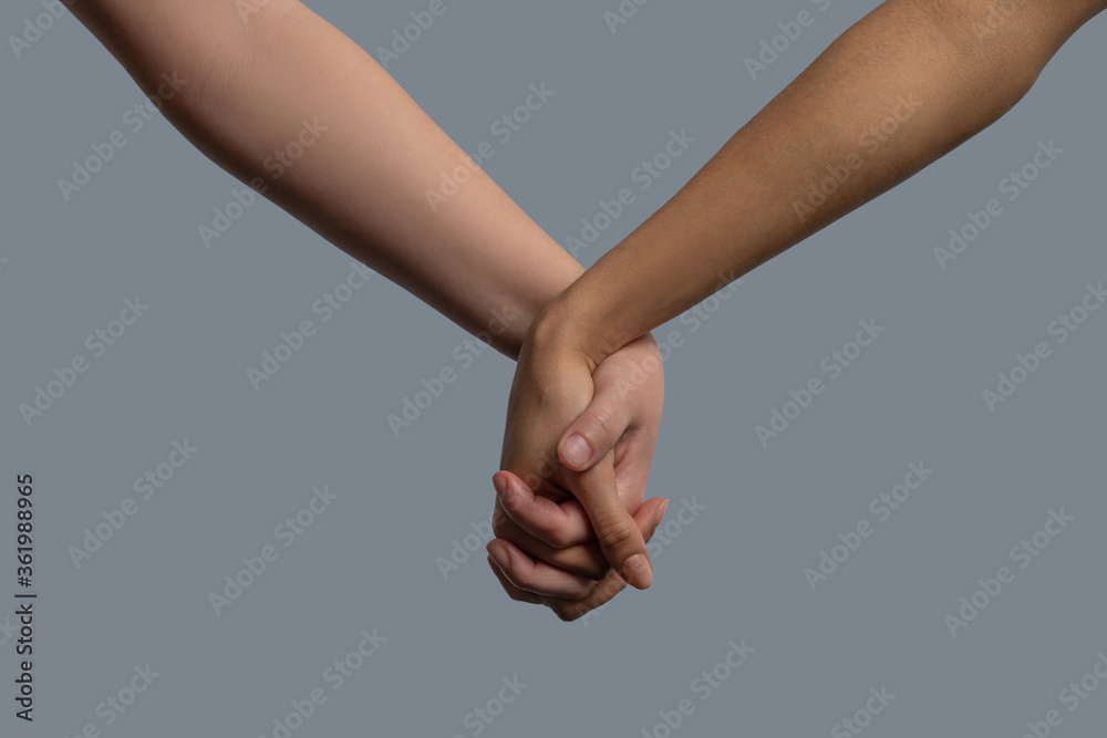 Close-up of light-skinned and dark-skinned people holding hands Close-up of light-skinned and dark-skinned people holding hands