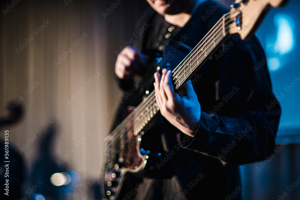 Obraz premium The musician plays the electric guitar on stage. Guitar neck close-up on a concert of rock music in the hands of a musician. Fingers on fretboard