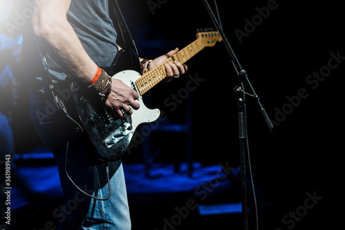 The guitarist plays the electric guitar. Guitar neck close-up on a concert of rock music in the hands of a musician. Fingers on fretboard