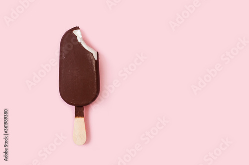 Helado de chocolate de palo batuta con una mordida sobre un fondo rosa pastel liso y aislado. Vista superior. Copy space