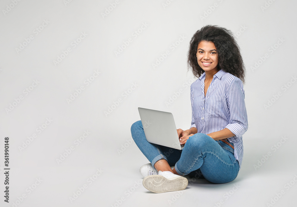 Portrait of a beautiful african woman with laptop on grey background Portrait of a beautiful african woman with laptop on grey background