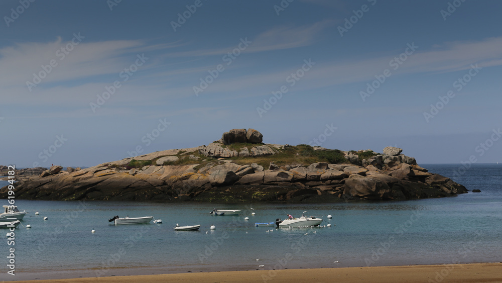Boats on a sunny day in the bay of the sandy beach of Coz-Porz with large granite boulders on the English Channel in Tregastel (Brittany, France)