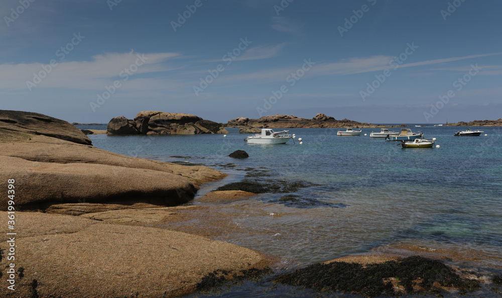 Boats on a sunny day in the bay of the sandy beach of Coz-Porz with large granite boulders on the English Channel in Tregastel (Brittany, France)