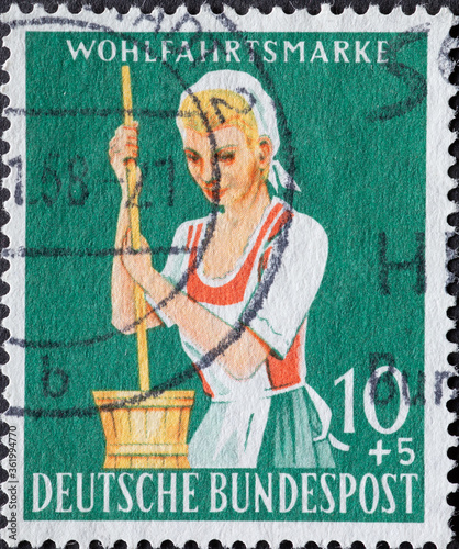 GERMANY - CIRCA 1958: a charitably  postage stamp printed in Germany showing a farmer with traditional costume, apron and headscarf during the historic butter production photo