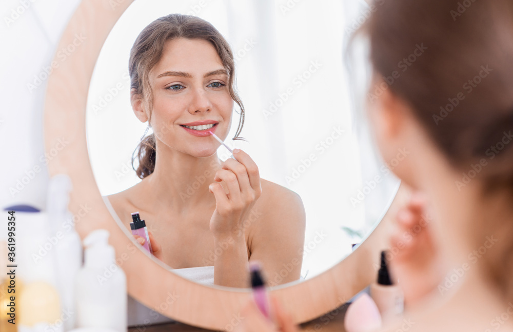 Beautiful lady applying lipstick in front of mirror Beautiful lady applying lipstick in front of mirror