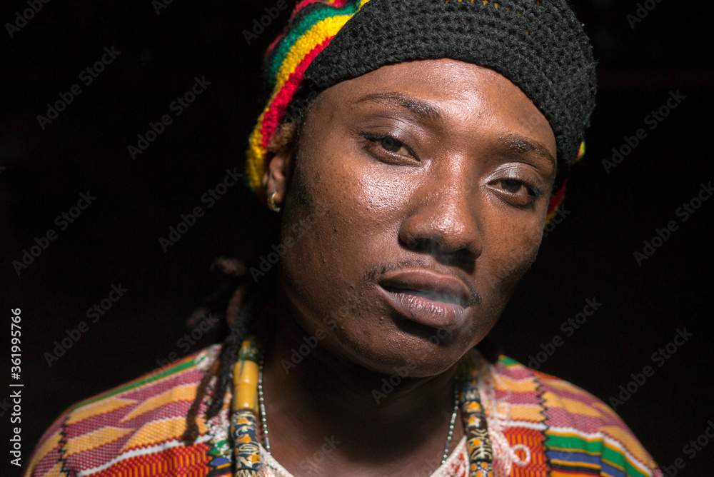 Obraz premium Face of young handsome African Rastafarian man smoking outdoors at night