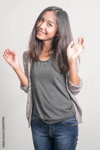 Happy young beautiful Asian teenage girl waving hand