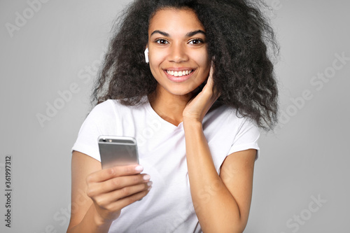 Beautiful african woman holding a phone in his hand on a gray background