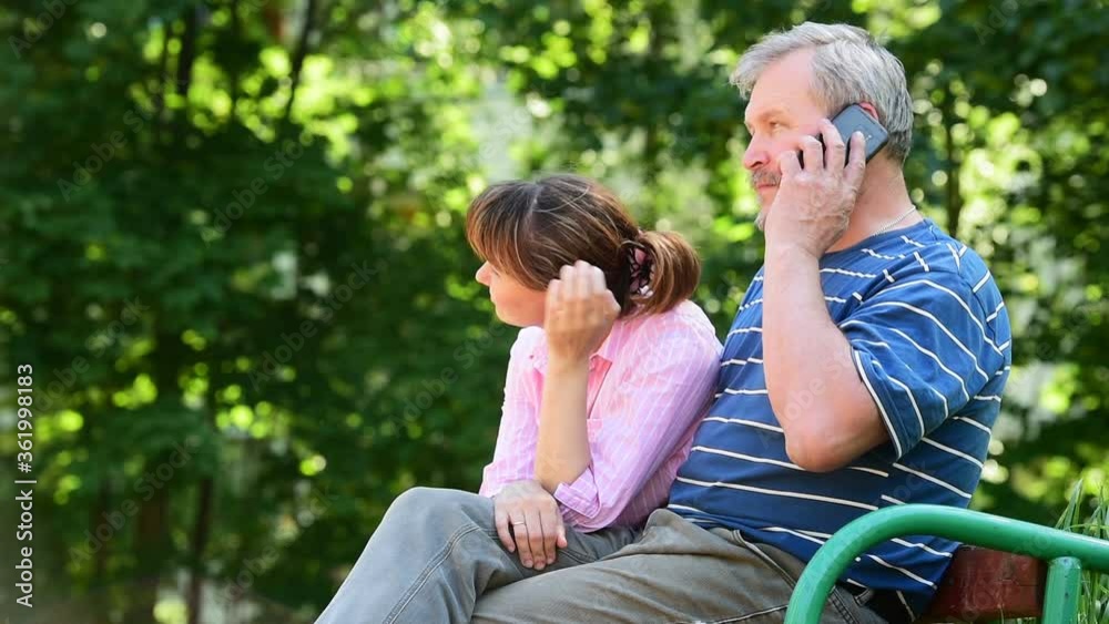 A couple in the Park a man on the phone and a bored woman A couple in the Park a man on the phone and a bored woman