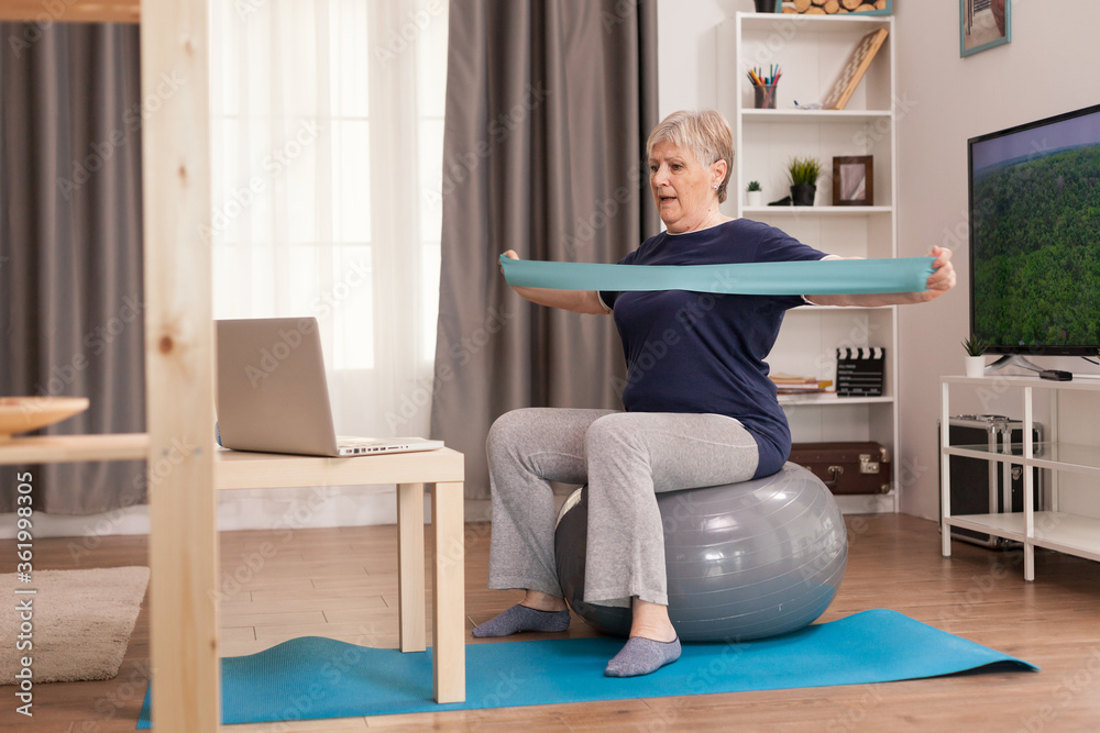 Elderly woman workout at home in front of the laptop. Old person