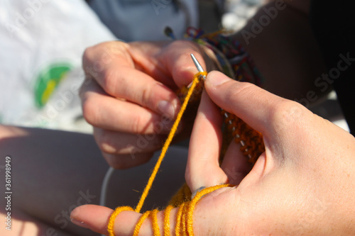 Knitting scene. Hand and knitting needles. Yellow and orange clothing. © taidundua