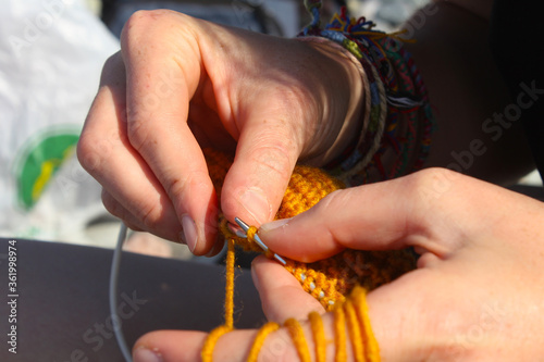 Knitting scene. Hand and knitting needles. Yellow and orange clothing.