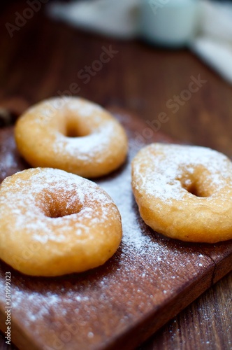 Three powdered sugar donuts on rustic table for snack food or breakfast. © Indah