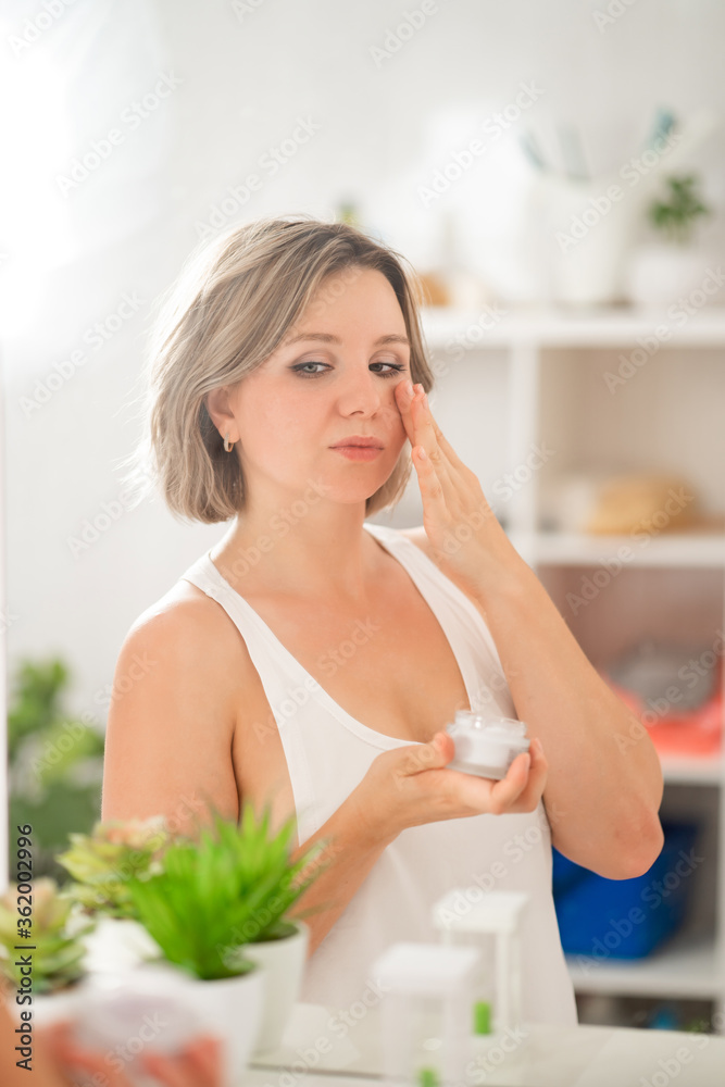 sexy girl with tattoos looks in mirror, apply cream on face and decollete area. sexy girl with tattoos looks in mirror, apply cream on face and decollete area.
