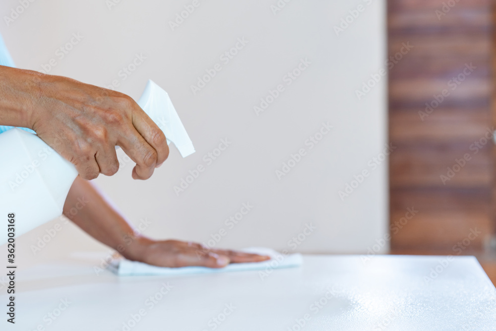 Asain maid worker is cleaning table with anti coronavirus cleanser in foggy before use. Asain maid worker is cleaning table with anti coronavirus cleanser in foggy before use.