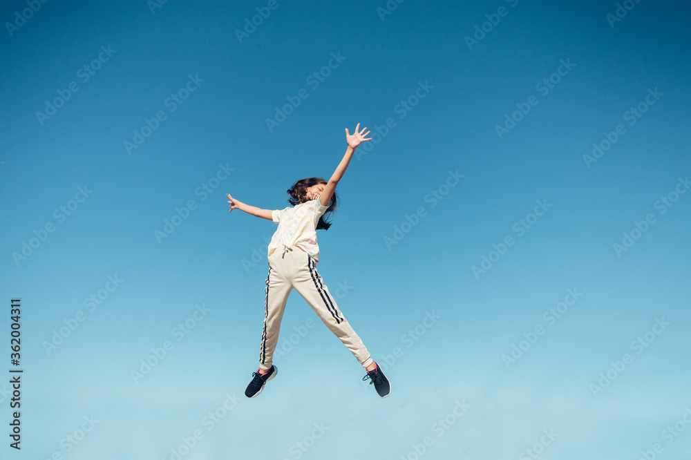 jump in the air. A girl in full height jumps in the air having fun on a bright blue turquoise background of the summer sky color. Selective focus