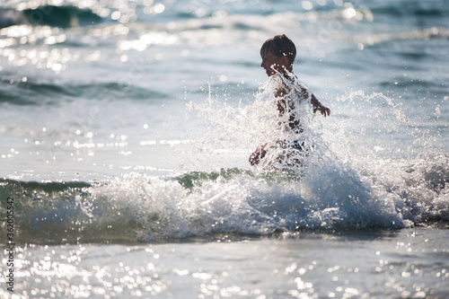A little boy on the beach, playing with the waves