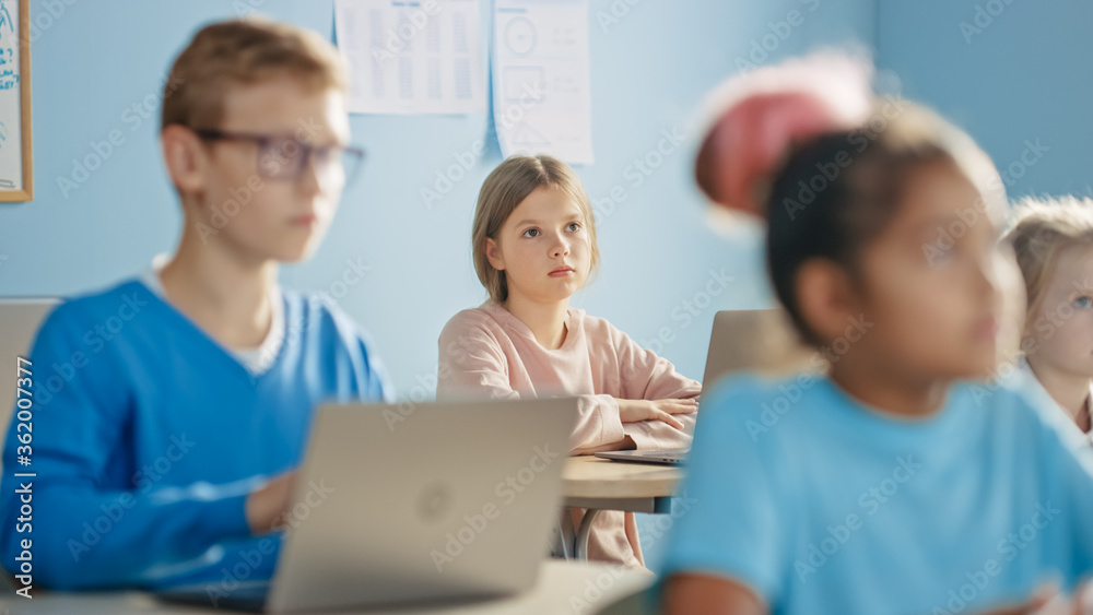 Elementary School Computer Science Class: Cute Girl Uses Digital Tablet Computer, Carefully Listening to a Teacher. Children Getting Modern Education in STEM, Playing and Learning. Elementary School Computer Science Class: Cute Girl Uses Digital Tablet Computer, Carefully Listening to a Teacher. Children Getting Modern Education in STEM, Playing and Learning.