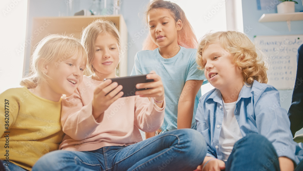 Diverse Group of Cute Small Children Sitting together on the Bean Bags Use Smartphone and Talk, Have Fun. Kids Browsing on Internet and Playing Online Video Games on Mobile Phone, Watching Videos Diverse Group of Cute Small Children Sitting together on the Bean Bags Use Smartphone and Talk, Have Fun. Kids Browsing on Internet and Playing Online Video Games on Mobile Phone, Watching Videos