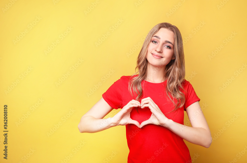 Beautiful woman showing heart on yellow background Beautiful woman showing heart on yellow background