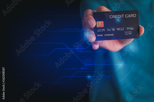 Shopping online concept. Hand holding credit card on technology background with copy space for text.