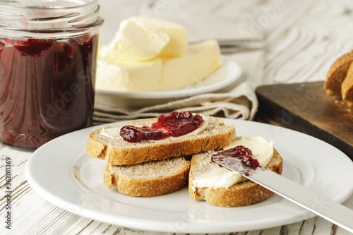 Slice of fresh bread with butter and jam on table