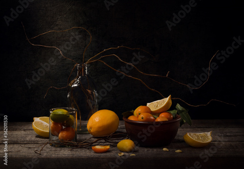 Still life with citrus fruits. Bright kumquat and lemon in vase on dark brown vintage background