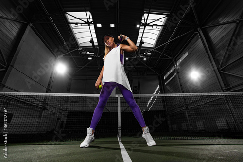 Woman tennis player posing like a fitness fashion model on tennis court.