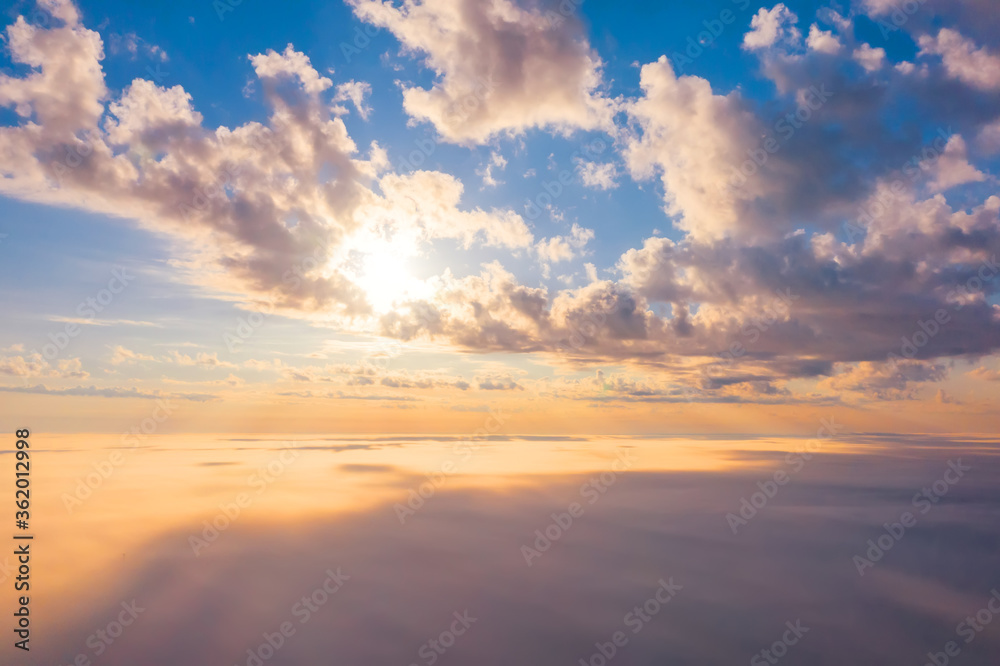 Dawn above the thick morning fog below, under the cumulus clouds, sunlight.