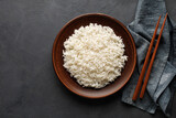 Boiled rice, chopsticks and napkin on a black concrete background. Asian food. Top view.