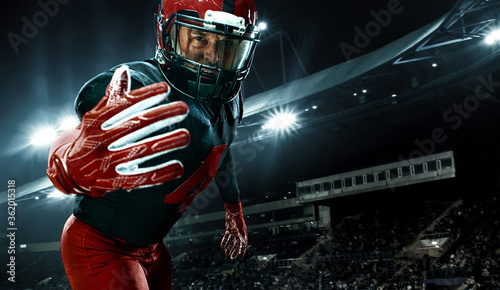 Closeup portrait of american football player, athlete sportsman in red helmet on grand arena background. Sport and motivation wallpaper.