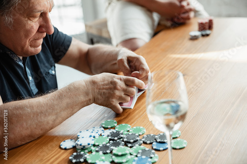 Exciting. Happy mature man playing cards and drinking wine with friends. Looks delighted, excited. Caucasian man gambling at home. Sincere emotions, wellbeing, facial expression concept. Good old age.