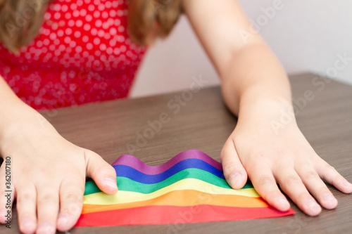 Girl hold flag Of Rainbow at home window during the Covid-19.