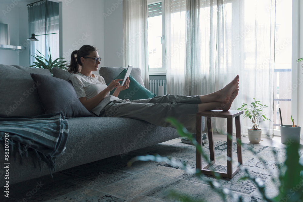 Woman relaxing on the sofa and connecting with her tablet Woman relaxing on the sofa and connecting with her tablet