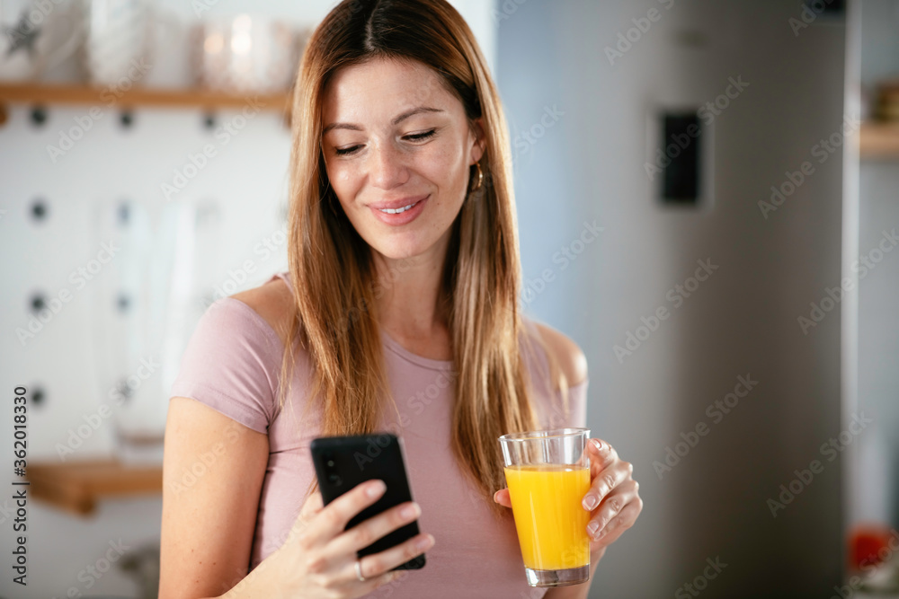 Young woman in the kitchen. Beautiful woman drinking orange juice and using the phone.
Young woman in the kitchen. Beautiful woman drinking orange juice and using the phone.
