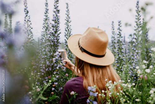 Beautiful girl in brown hat among purple wildflowers in field. Concept of freedom, travel, lifestyle. photo