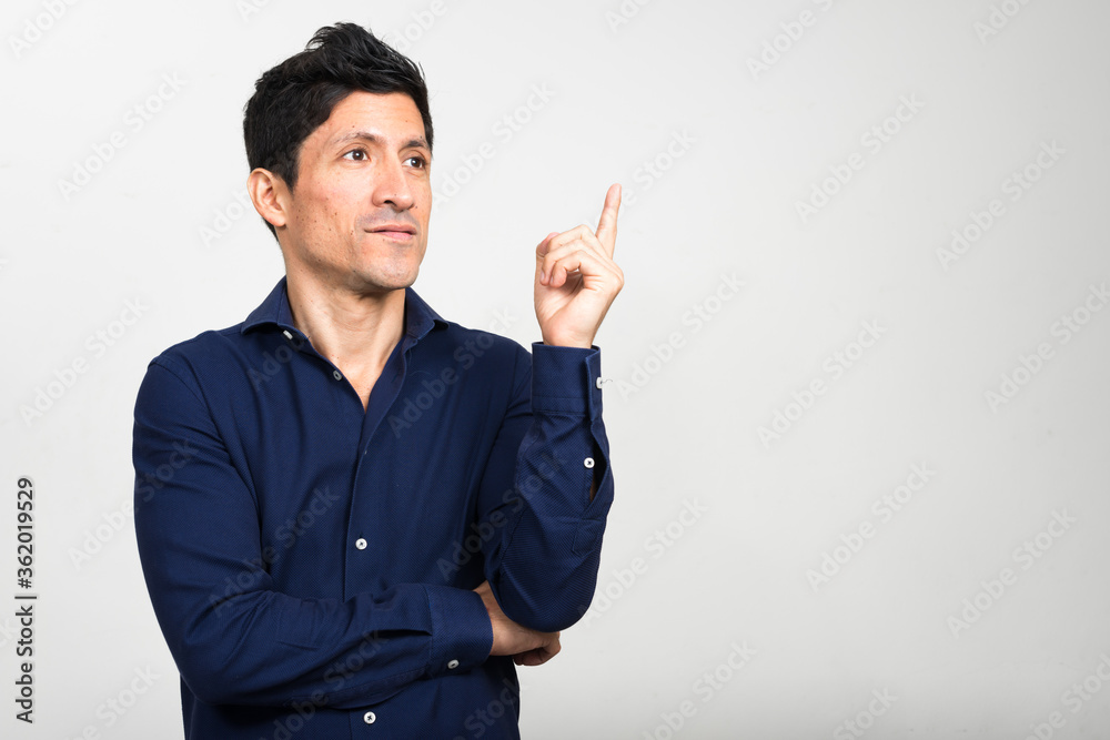 Portrait of Hispanic businessman thinking and pointing up Portrait of Hispanic businessman thinking and pointing up
