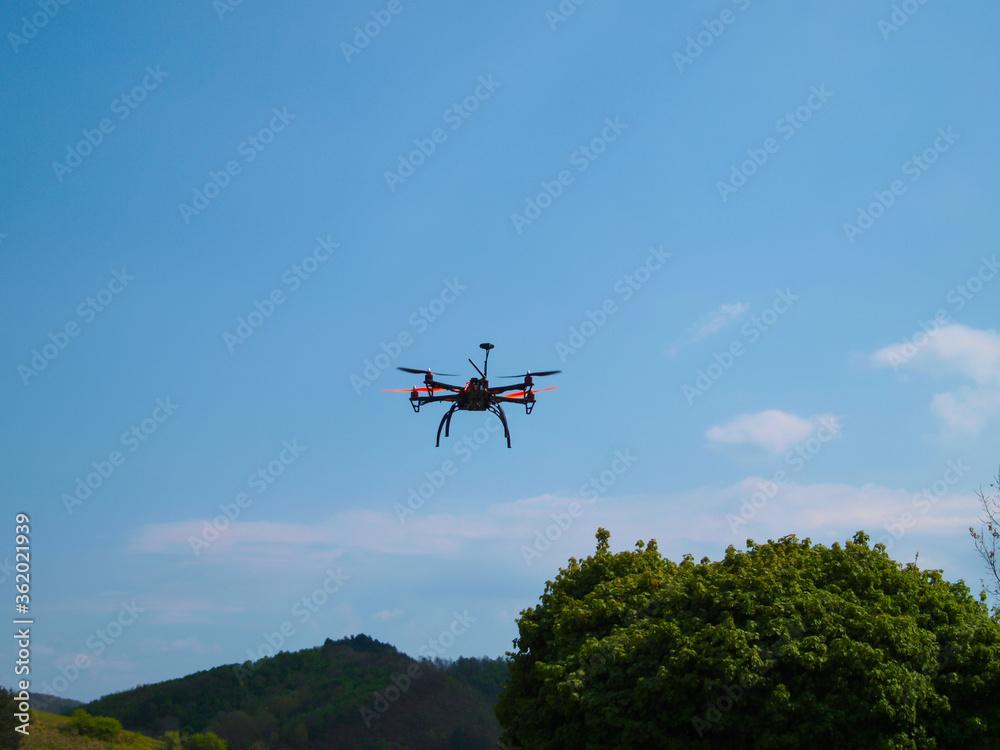 Fototapeta premium Flying drone in the blue sky. Mountains in the background.
