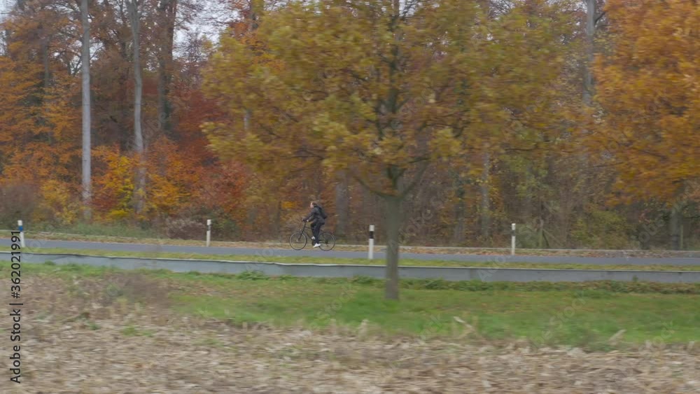 Dynamic drone shot of a young man driving down a road on bicycle in a beautiful autumn landscape. Dynamic drone shot of a young man driving down a road on bicycle in a beautiful autumn landscape.
