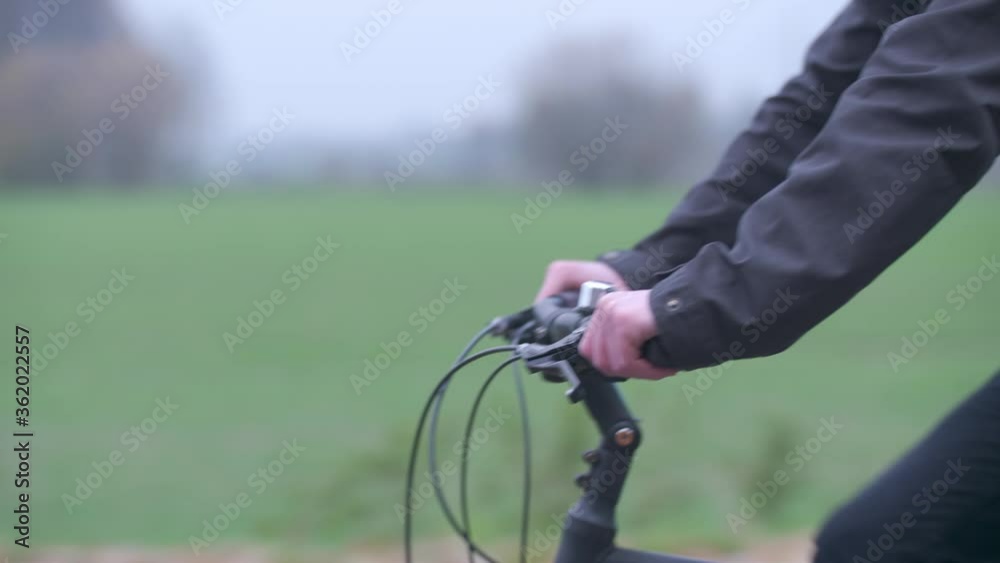 Detail of a young man driving a bicycle on a road in autumn. Detail of a young man driving a bicycle on a road in autumn.