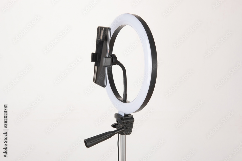 Obraz premium The camera fill light for the phone is mounted on a tripod, which is a device for shooting vlogs and doing live broadcasts.