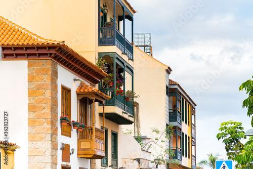 Colorful buildings with a wooden balconies on a street in spanish town Puerto de la Cruz on a sunny day, Tenerife, Canary islands, Spain. © garrykillian