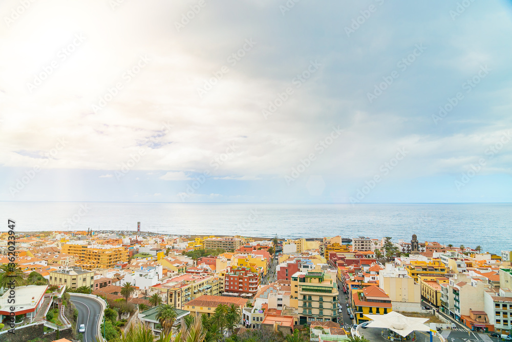 Landscape of the city by the ocean with a blue ske with clouds. Puerto de La Cruz on a sunny day. Tenerife, Spain