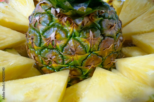 jiucy pineapple slices together with pinapple on a plate. photo